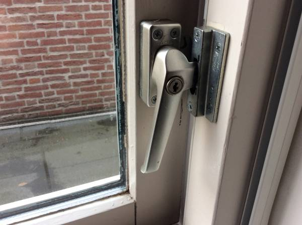 Een raamsluiting met een cilinder slot erop
